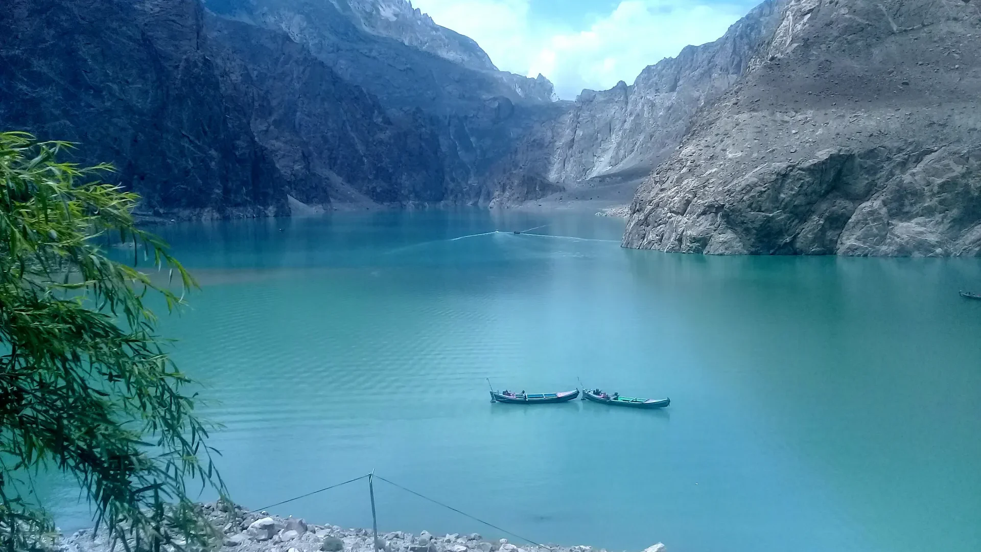 Turquoise water of Attabad Lake between steep Karakoram cliffs